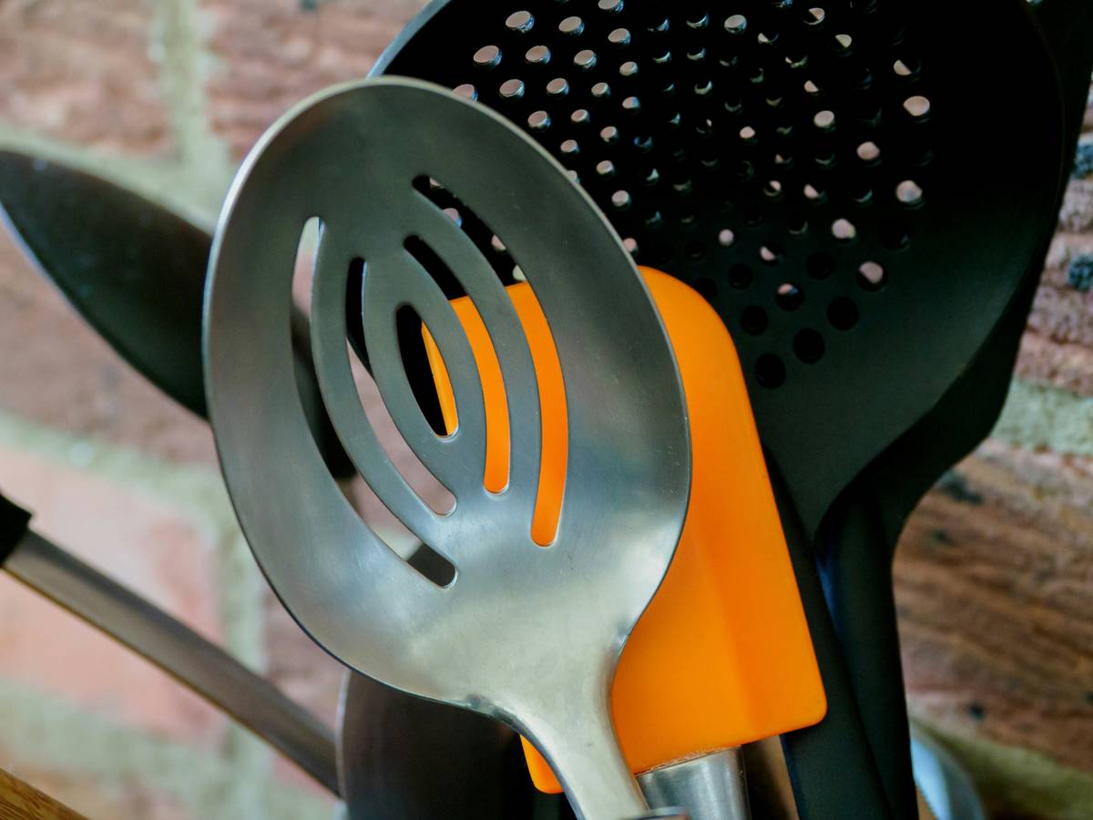 Close-up of hand holding a potato peeler ergonomic handle while peeling a potato